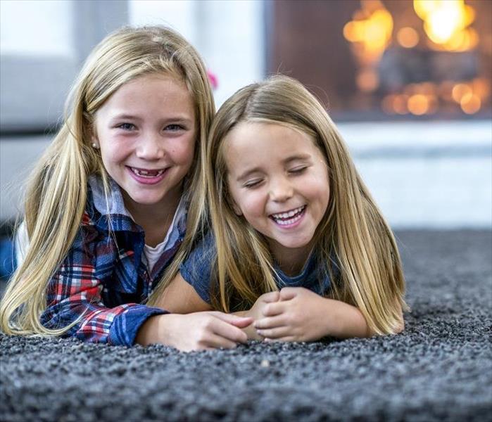 Two girls laying an carpeted floor